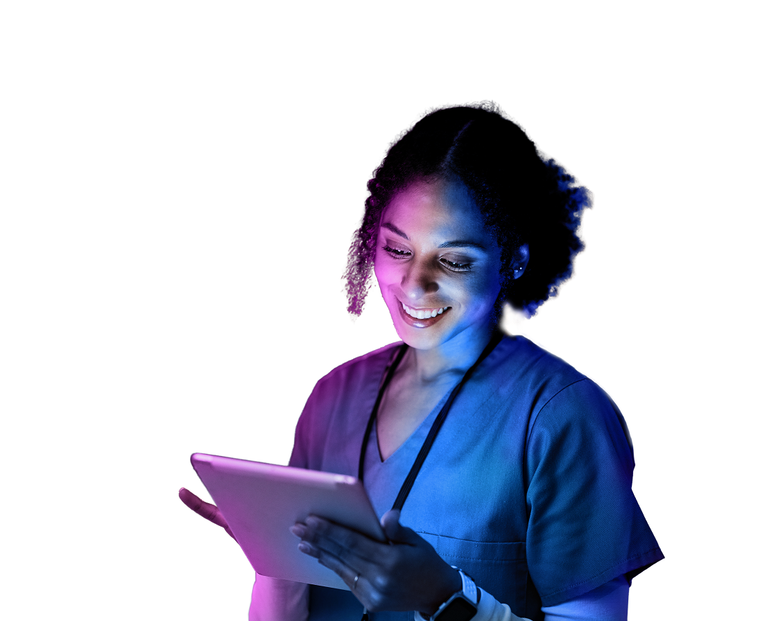 Smiling nurse in scrubs using a tablet, illuminated by colorful lighting against a dark background.